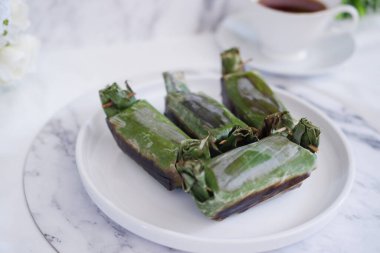 Lemper Bakar. Lemper, glutinous pirinçten yapılmış ve tavuk etiyle doldurulmuş ve muz yapraklarına sarılmış geleneksel bir Endonezya aperatifi. Seçici odak