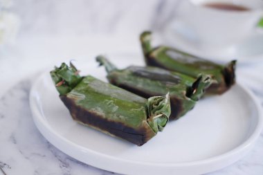 Lemper Bakar. Lemper, glutinous pirinçten yapılmış ve tavuk etiyle doldurulmuş ve muz yapraklarına sarılmış geleneksel bir Endonezya aperatifi. Seçici odak