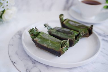 Lemper Bakar. Lemper, glutinous pirinçten yapılmış ve tavuk etiyle doldurulmuş ve muz yapraklarına sarılmış geleneksel bir Endonezya aperatifi. Seçici odak