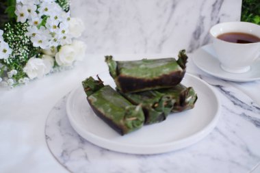 Lemper Bakar. Lemper, glutinous pirinçten yapılmış ve tavuk etiyle doldurulmuş ve muz yapraklarına sarılmış geleneksel bir Endonezya aperatifi. Seçici odak