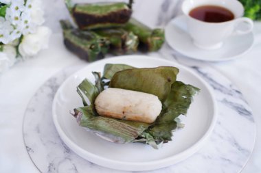 Lemper Bakar. Lemper, glutinous pirinçten yapılmış ve tavuk etiyle doldurulmuş ve muz yapraklarına sarılmış geleneksel bir Endonezya aperatifi. Seçici odak