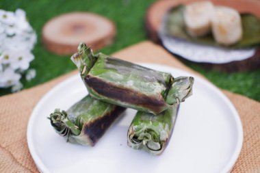 Lemper Bakar. Lemper, glutinous pirinçten yapılmış ve tavuk etiyle doldurulmuş ve muz yapraklarına sarılmış geleneksel bir Endonezya aperatifi. Seçici odak