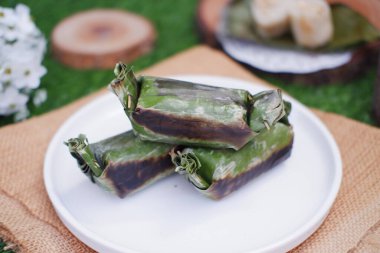 Lemper Bakar. Lemper, glutinous pirinçten yapılmış ve tavuk etiyle doldurulmuş ve muz yapraklarına sarılmış geleneksel bir Endonezya aperatifi. Seçici odak
