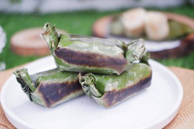 Lemper Bakar. Lemper, glutinous pirinçten yapılmış ve tavuk etiyle doldurulmuş ve muz yapraklarına sarılmış geleneksel bir Endonezya aperatifi. Seçici odak