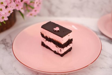 Arkaplan olarak pembe tabakta bir parça çikolatalı kek.