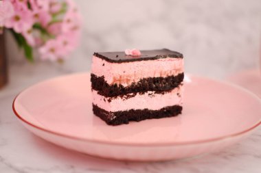Arkaplan olarak pembe tabakta bir parça çikolatalı kek.