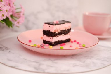 Arkaplan olarak pembe tabakta bir parça çikolatalı kek.