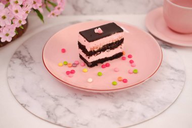 Arkaplan olarak pembe tabakta bir parça çikolatalı kek.