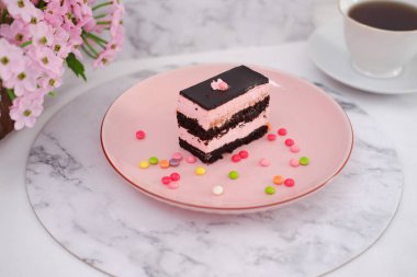 Arkaplan olarak pembe tabakta bir parça çikolatalı kek.