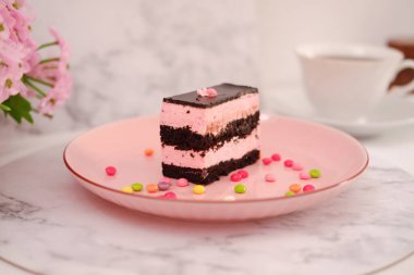 Arkaplan olarak pembe tabakta bir parça çikolatalı kek.