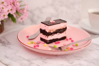 Arkaplan olarak pembe tabakta bir parça çikolatalı kek.