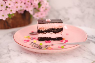 Arkaplan olarak pembe tabakta bir parça çikolatalı kek.