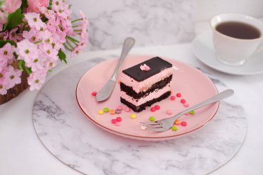 Arkaplan olarak pembe tabakta bir parça çikolatalı kek.