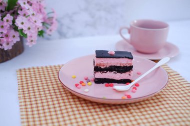 Arkaplan olarak pembe tabakta bir parça çikolatalı kek.