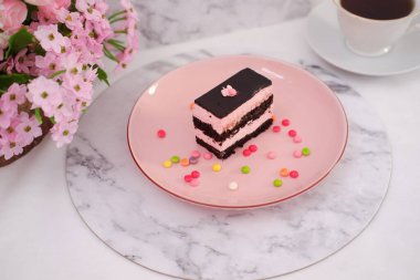 Arkaplan olarak pembe tabakta bir parça çikolatalı kek.