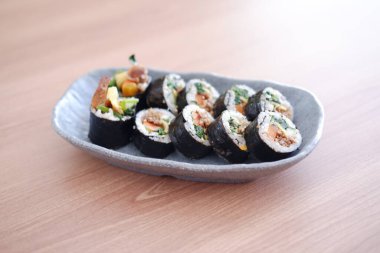Suşi Japon yemeği tarzında ahşap masa arkasında yuvarlanıyor..