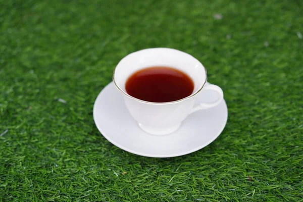 Cup of tea on green grass background, shallow depth of field
