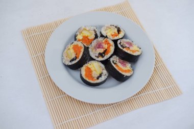 Suşi beyaz arka planda bir tabakta yuvarlanıyor. Japon yemeği.