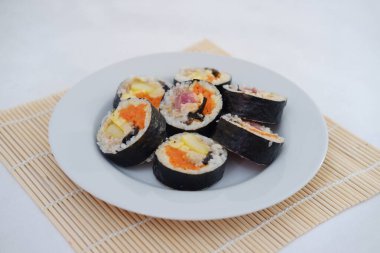 Suşi beyaz arka planda bir tabakta yuvarlanıyor. Japon yemeği.