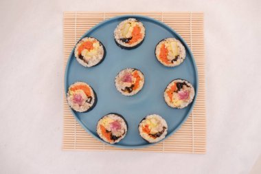 Suşi beyaz arka planda bir tabakta yuvarlanıyor. Japon yemeği.
