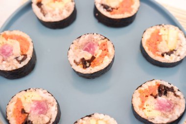 Suşi beyaz arka planda bir tabakta yuvarlanıyor. Japon yemeği.