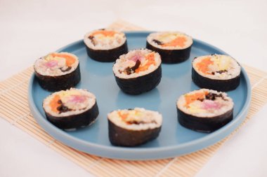 Suşi beyaz arka planda bir tabakta yuvarlanıyor. Japon yemeği.