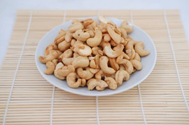 Kavrulmuş kaju fıstığı beyaz kasede bambu hasırı üzerinde, stok fotoğrafı.