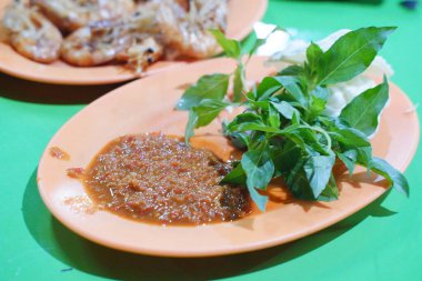 Turuncu tabakta fesleğen yapraklı baharatlı acı biber sosu.