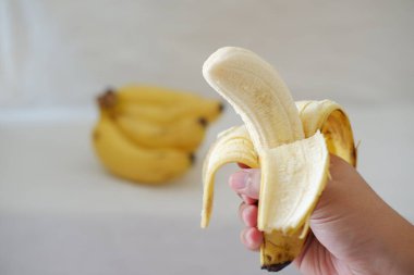 Tahta bir tabakta bir kızın ellerinde muz. Seçici odak.