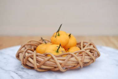 Sarı mandalinalar mermer bir masada hasır sepetin içinde