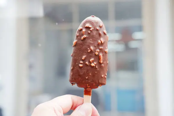 Chocolate ice cream on stick in hand