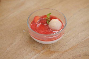 Tahta masadaki bardakta çilekli puding.