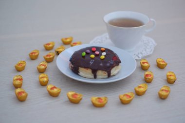 Donut with chocolate glaze and cup of tea on the table clipart