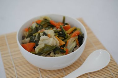 Bambu hasırı üzerinde beyaz bir kasede Capcay