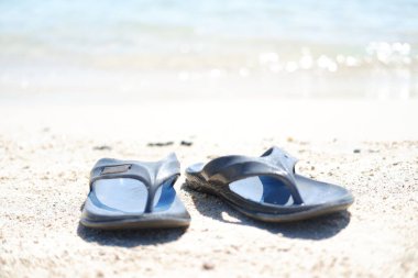 Sahildeki deniz altyapısı olan kumsalda parmak arası terlikler.