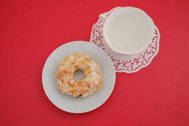 Üzerinde donut ve bir fincan olan beyaz bir tabak enfes ve iştah açıcı bir görüntü yaratıyor..