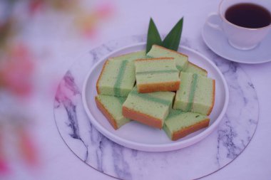 beyaz tabakta pandan keki bir fincan çayla