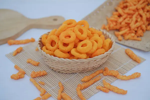 Bambu hasırında beyaz arka planda bir sepette atıştırmalık peynir krakerleri..