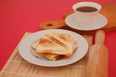 Kırmızı arka planda izole edilmiş beyaz tabakta kızarmış ekmek..