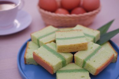 Mavi tabakta pandan keki ve bir fincan çay.