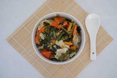 Bambu hasırı üzerinde beyaz bir kasede Capcay