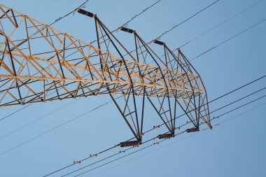 Mavi gökyüzüne karşı yüksek voltajlı elektrik hatları. Elektrik dağıtım istasyonu.