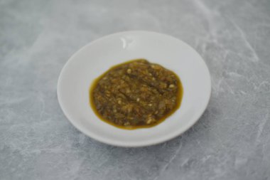 Mermer bir masada beyaz bir kasede yeşil sambal..
