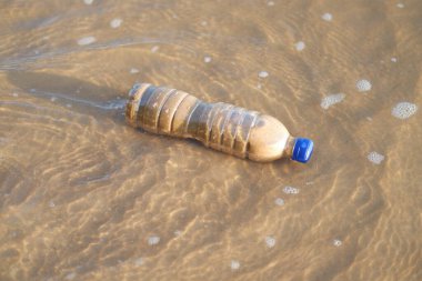 Plajda plastik şişe, yumuşak odaklı fotoğrafa yakın çekim.