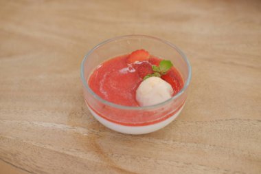 Tahta masadaki bardakta çilekli puding.