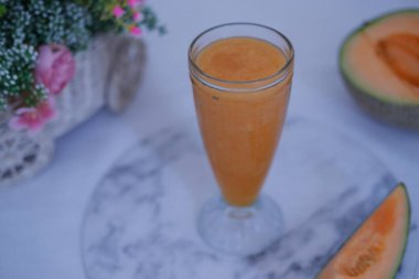 Bardakta kavun suyu ve masada taze kavun.