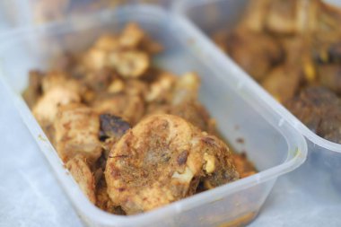 Baharatlı tavuk dolu üç plastik kap.