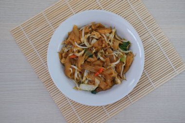 Sebzeli kızarmış erişte, fasulye filizi ve bambu hasırında servis edilen acı biber dilimleri.