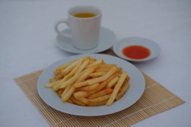 Çıtır patates kızartması yanında bambu hasırında kırmızı sos servis edilir.