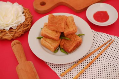 Bir tabak kızarmış tofu, güzelce düzenlenmiş ve yeşil biberle süslenmiş.